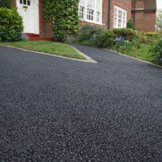 Close up of a tarmac driveway and path leading to the front door of brick home