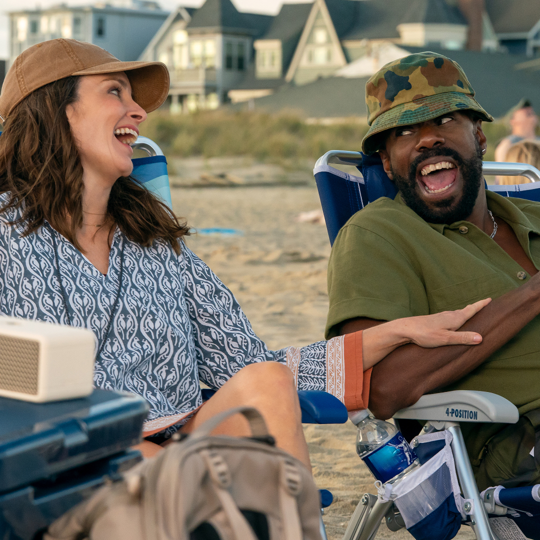 Tina Fey as Kate and Colman Domingo as Danny, laughing while sitting on the beach, in Episode 203 of The Four Seasons, Season 2.