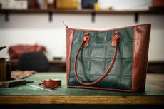 Brown and green leather bag on work table