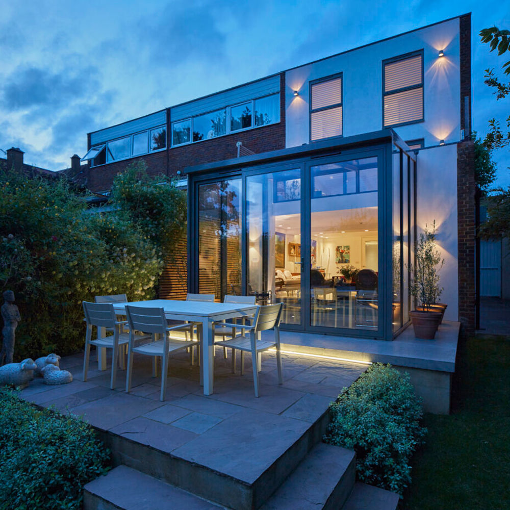 Evening time outside a small conservatory style extension on a small terrace house