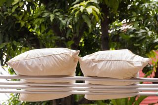 Two pillows are drying on a clothes airer outside after being washed