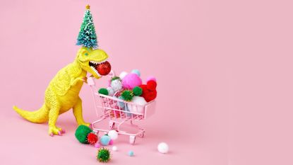 Yellow T Rex with a Christmas tree on his head and a shopping cart filled with baubles