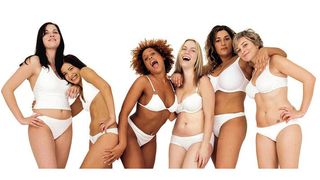 Group of women of different body shapes laughing and smiling in their underwear