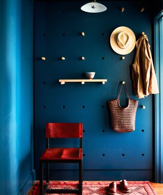 hallway with blue pegboard walls and hat and bag on peg