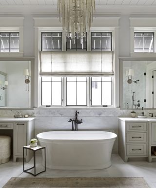 freestanding bath with statement chandelier in white bathroom, modern farmhouse