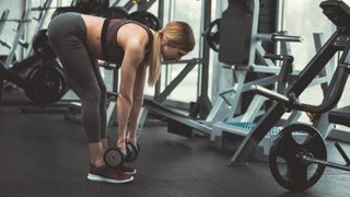 Woman performs stiff-leg Romanian deadlift in a gym with dumbbells