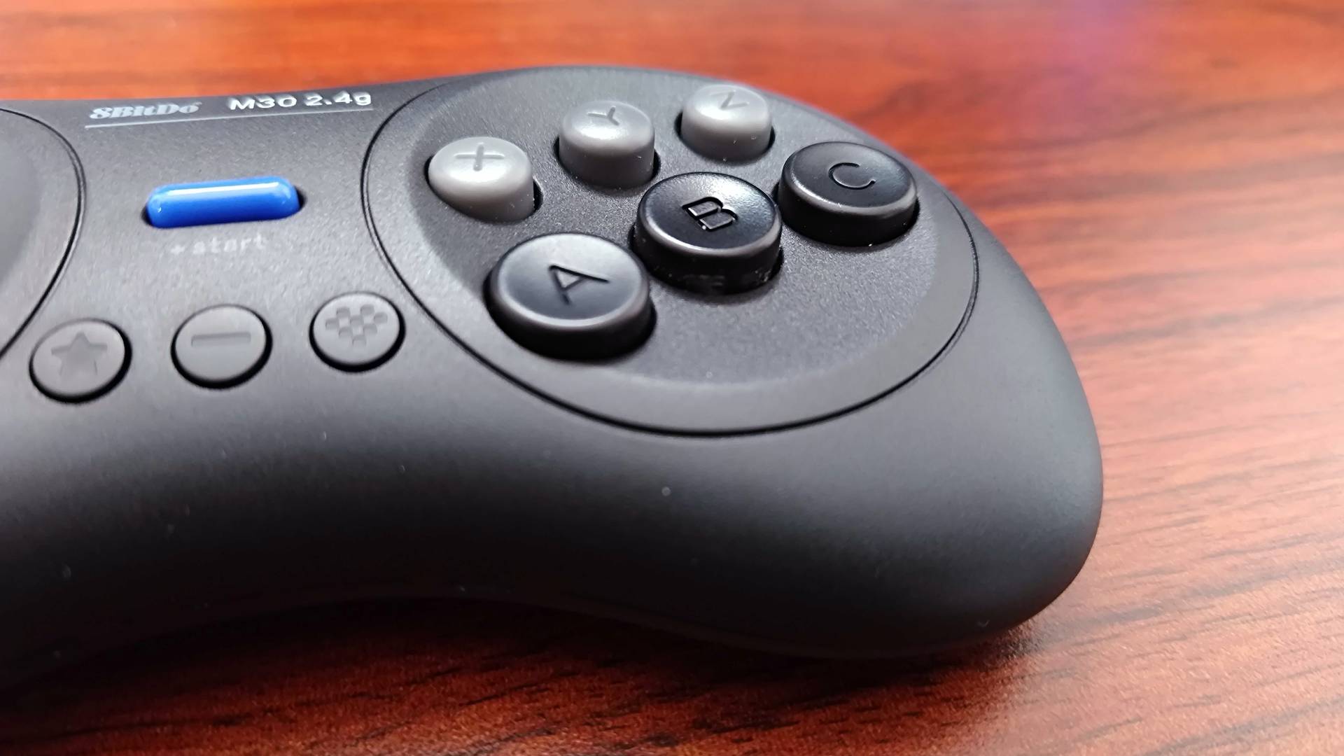 Close up of 8Bitdo M30 buttons on woodgrain desk.
