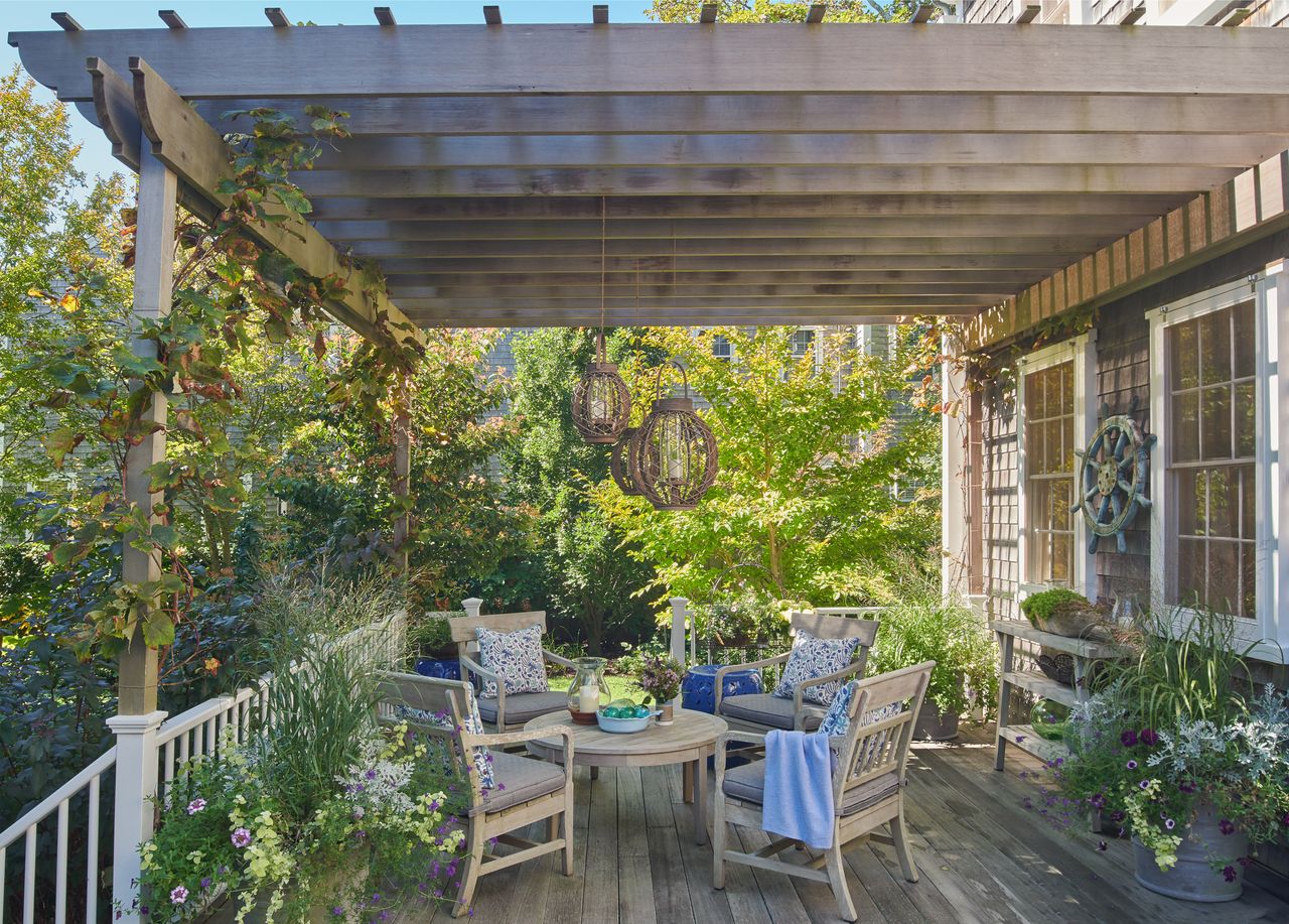 A patio features white and blue fabric home accessories along wooden chairs and tables.