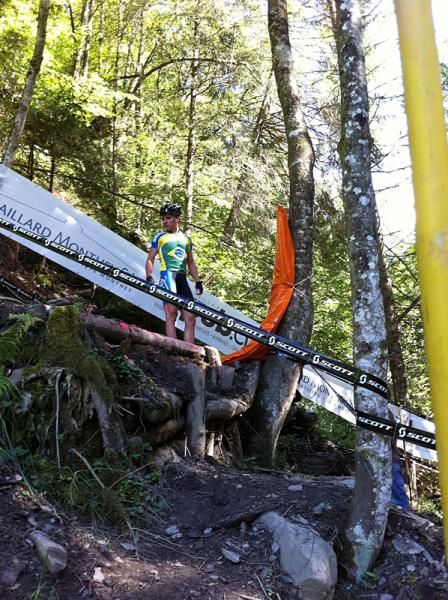 A rider stands next to a rather tall jump on the A-line at Hell's Gate