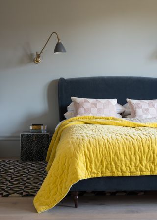 bedroom with a bright yellow chunky throw and grey walls and a blue headboard