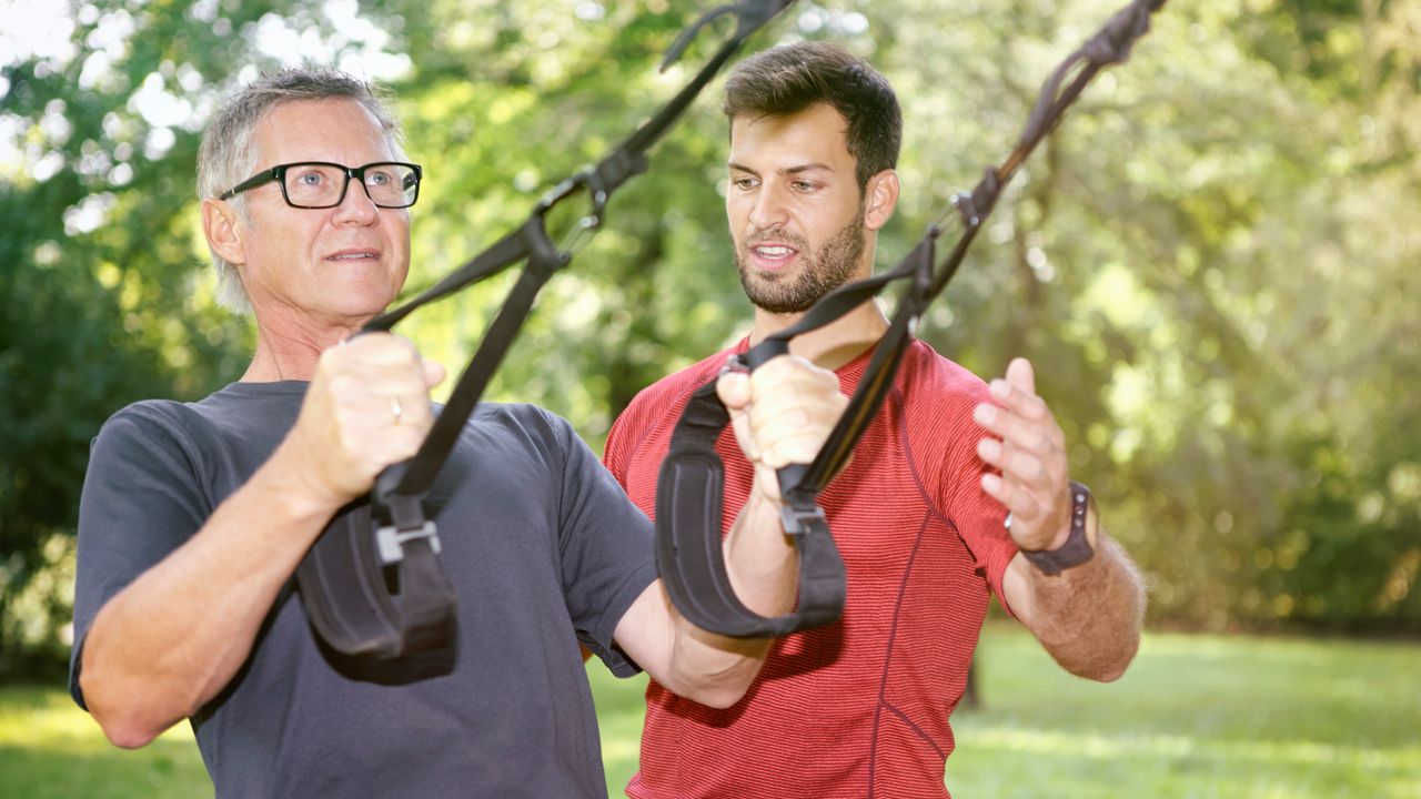 Man doing TRX exercises with a personal trainer