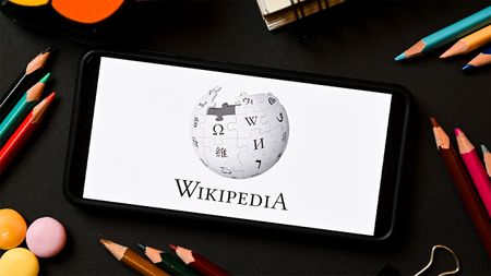 Wikipedia logo on smartphone with coloured pencils surrounding it