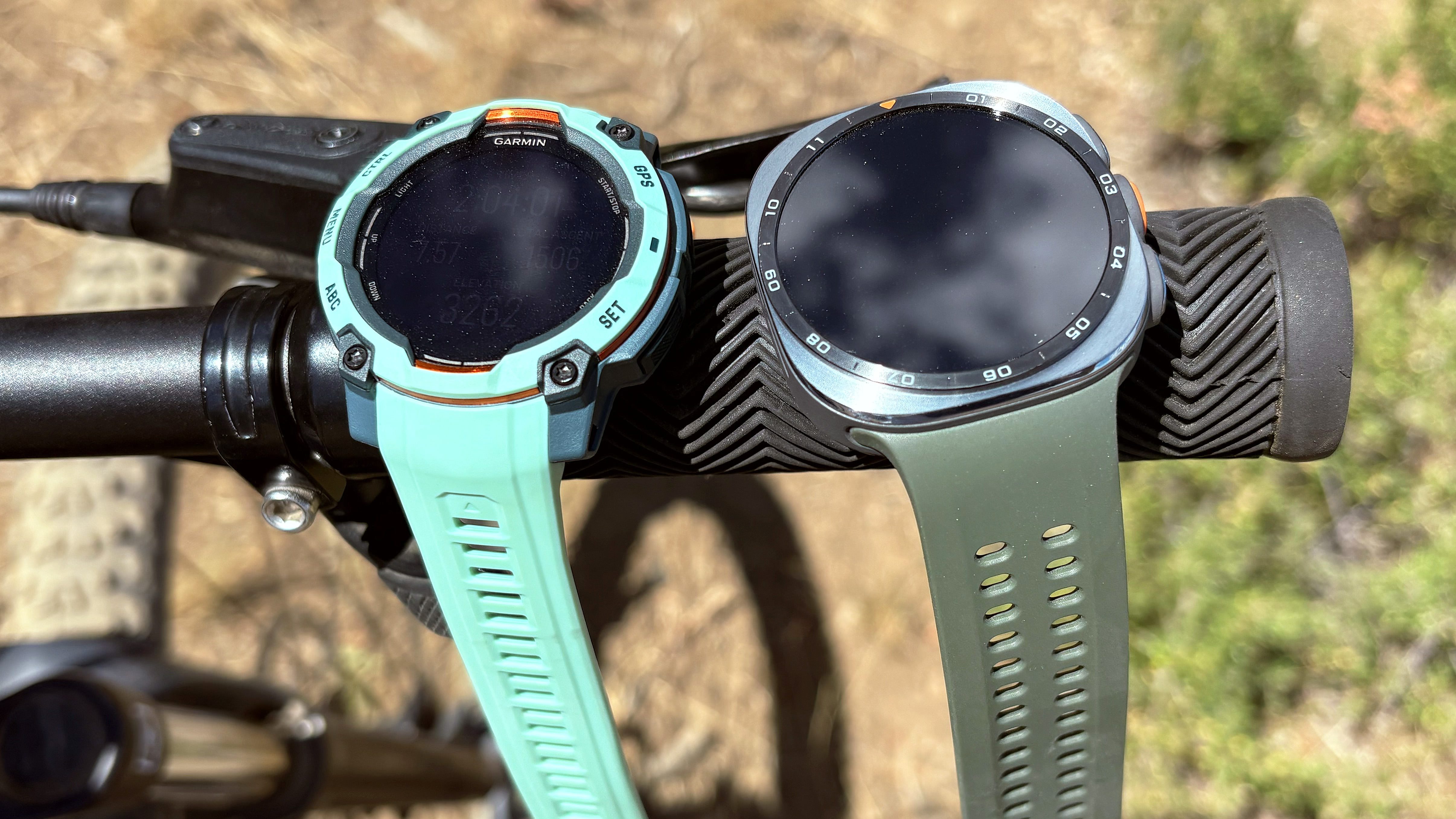 Close-up of the Samsung Galaxy Watch Ultra 2 and Garmin Instinct 3 in the mountains during an e-biking excursion 