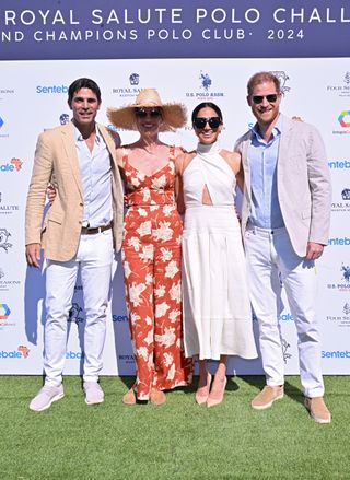 Nacho Figueras, Delfina Blaquier, Meghan Markle, Prince Harry posing in dressy summer clothes in front of a white backdrop at a polo match