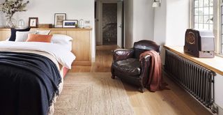 Bedroom with wooden headboard and wooden floors with pewter cast iron radiator to regulate room temperature
