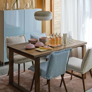 IKEA KLINTEN chairs around a dining table with a pink rug, blue cabinet, and vases on top