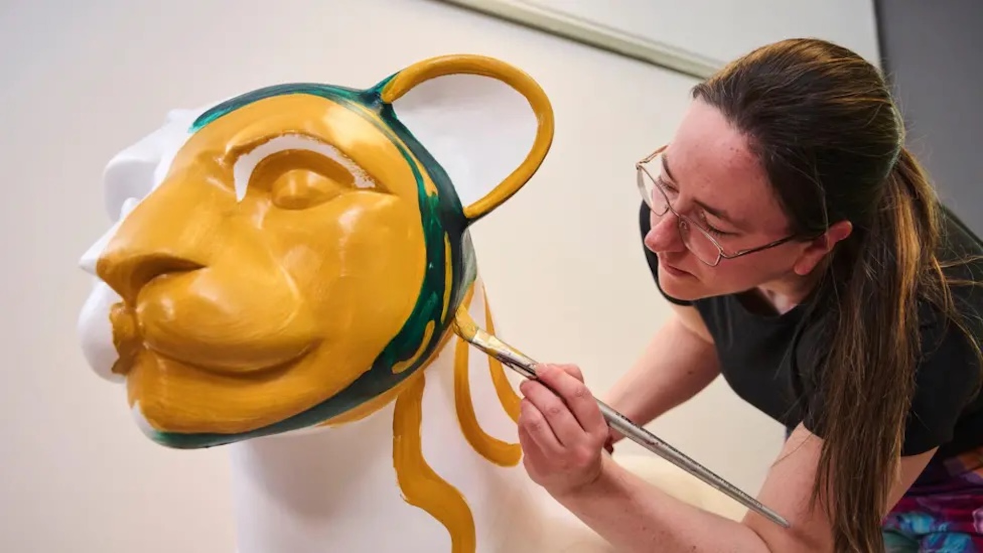 A person painting a lion sculpture