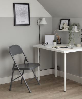 Gray folding chair in front of white desk