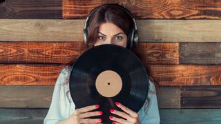 Woman holding vinyl record with wood paneling in background