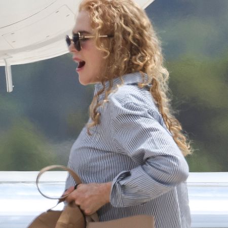Nicole Kidman boards a private jet in Ibiza, carrying The Row's N/S Park Tote in tan, and wearing cuffed jeans, a button-down shirt, and white sneakers.
