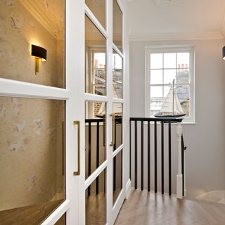 Antiqued mirror panels on the wall with black railing and stairs going down