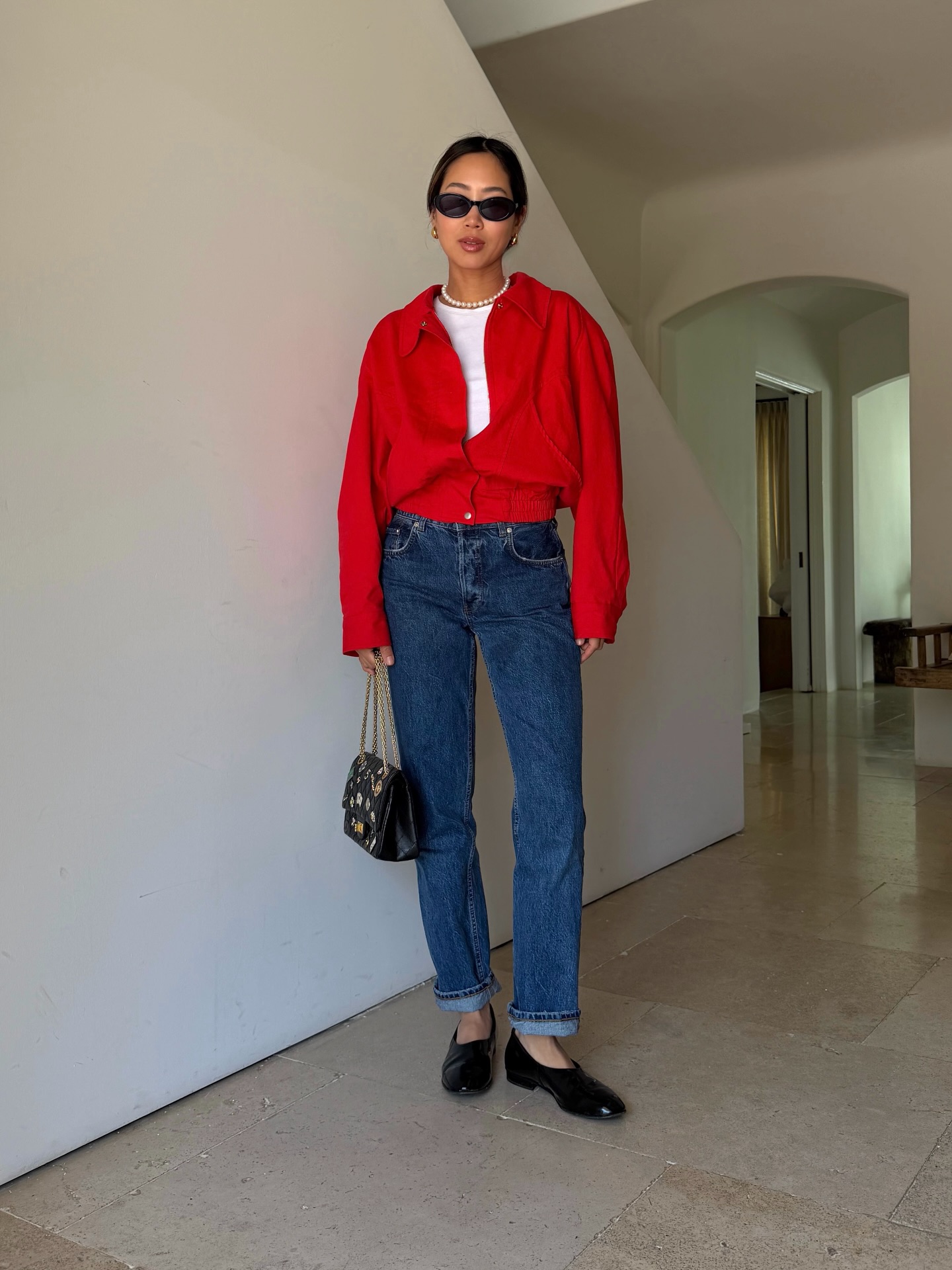 Influencer Aimee Song wears a red jacket, straight leg jeans and a black ballet flat.