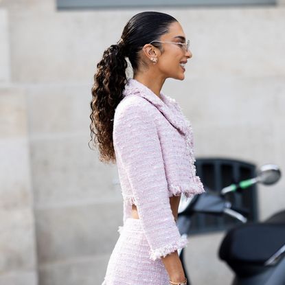 Woman wearing a pink tweed skirt suit, wearing her heritage brunette hair in a ponytail