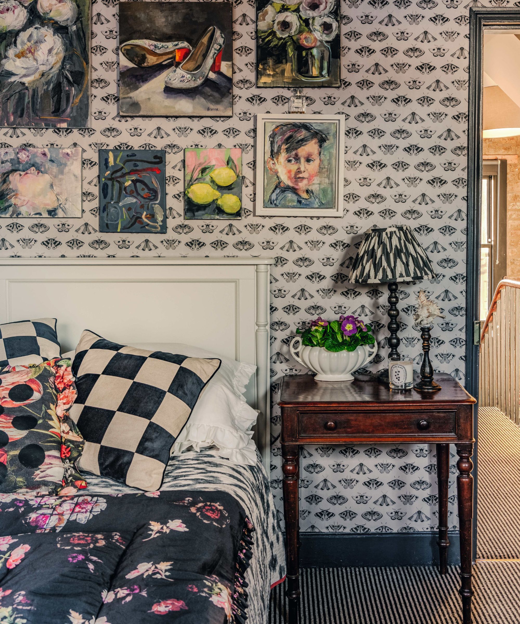 a monochrome bedroom with butterfly bedroom, vintage art, flower bedspread and checkerboard cushions