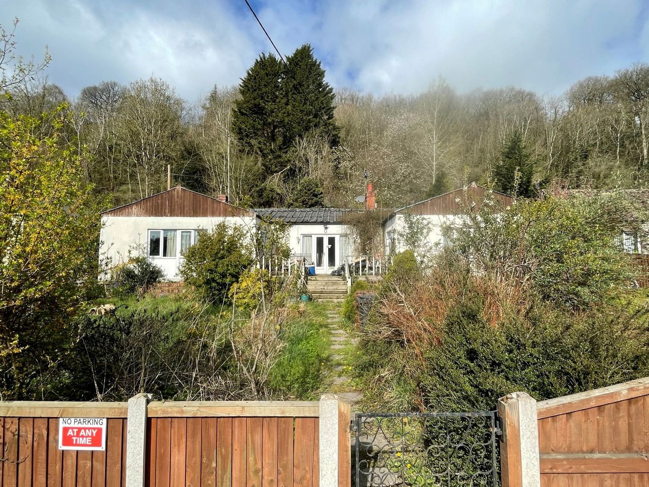 The entrance to the bungalow and the sloped front garden which leads to the entrance is overgrown