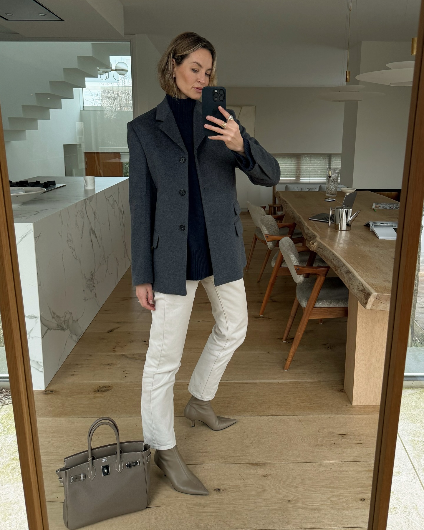 An image of @anoukyve wearing white bootcut jeans with grey pointed-toe ankle boots.