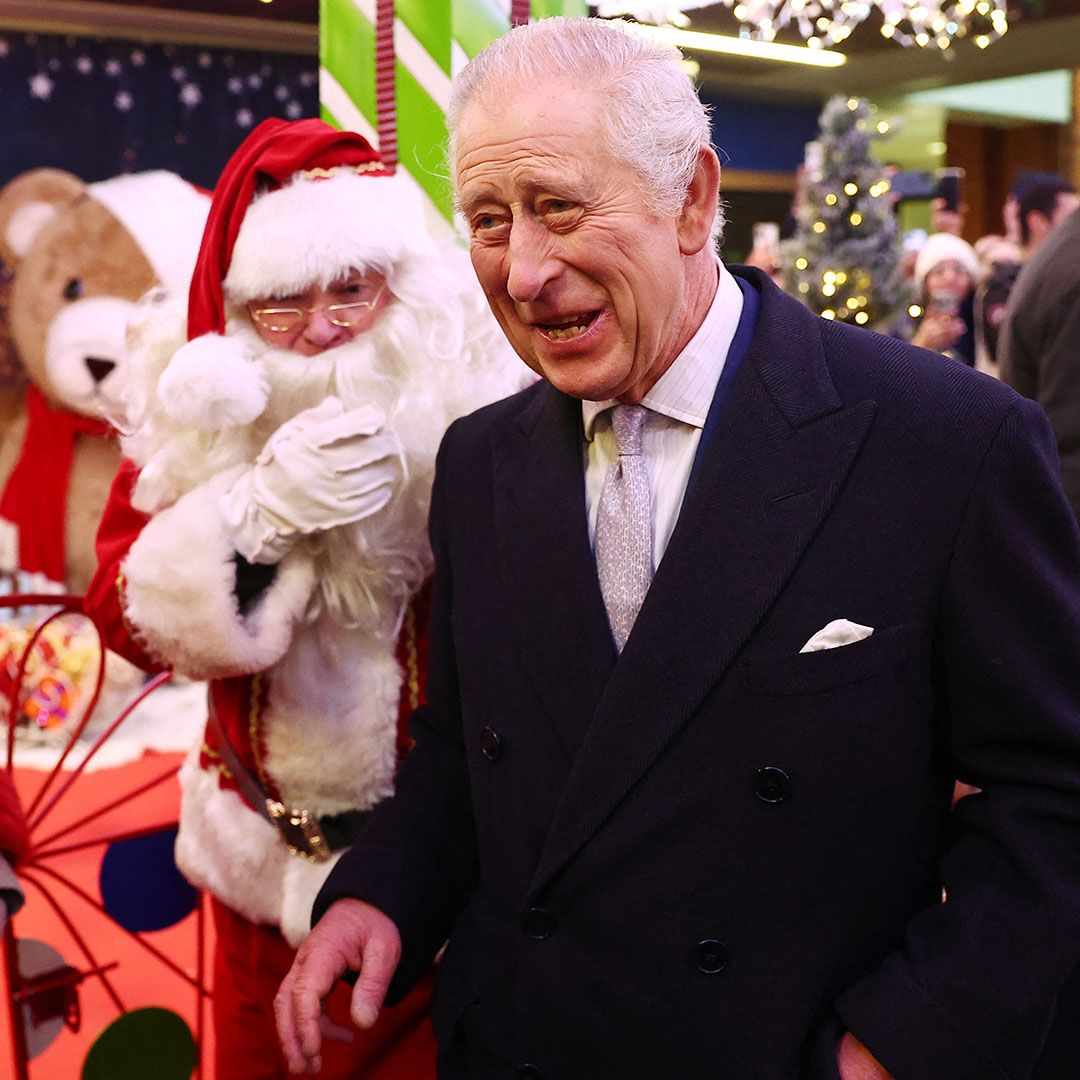 King Charles III smiling while meeting Santa Claus at a shopping center in west London.
