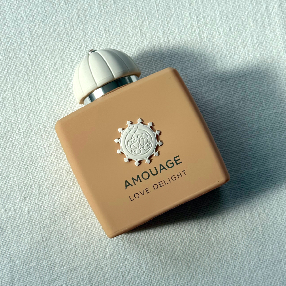 Bird&#039;s eye view of Amouage Love Delight Eau de Parfum against a white linen background