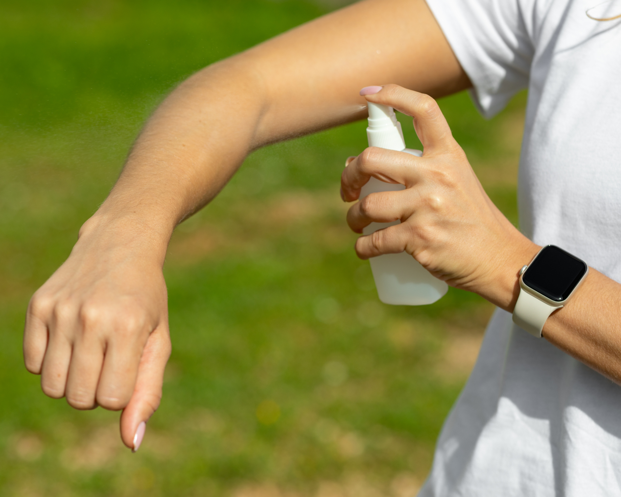 Woman spraying mosquito insect repellent on her arm