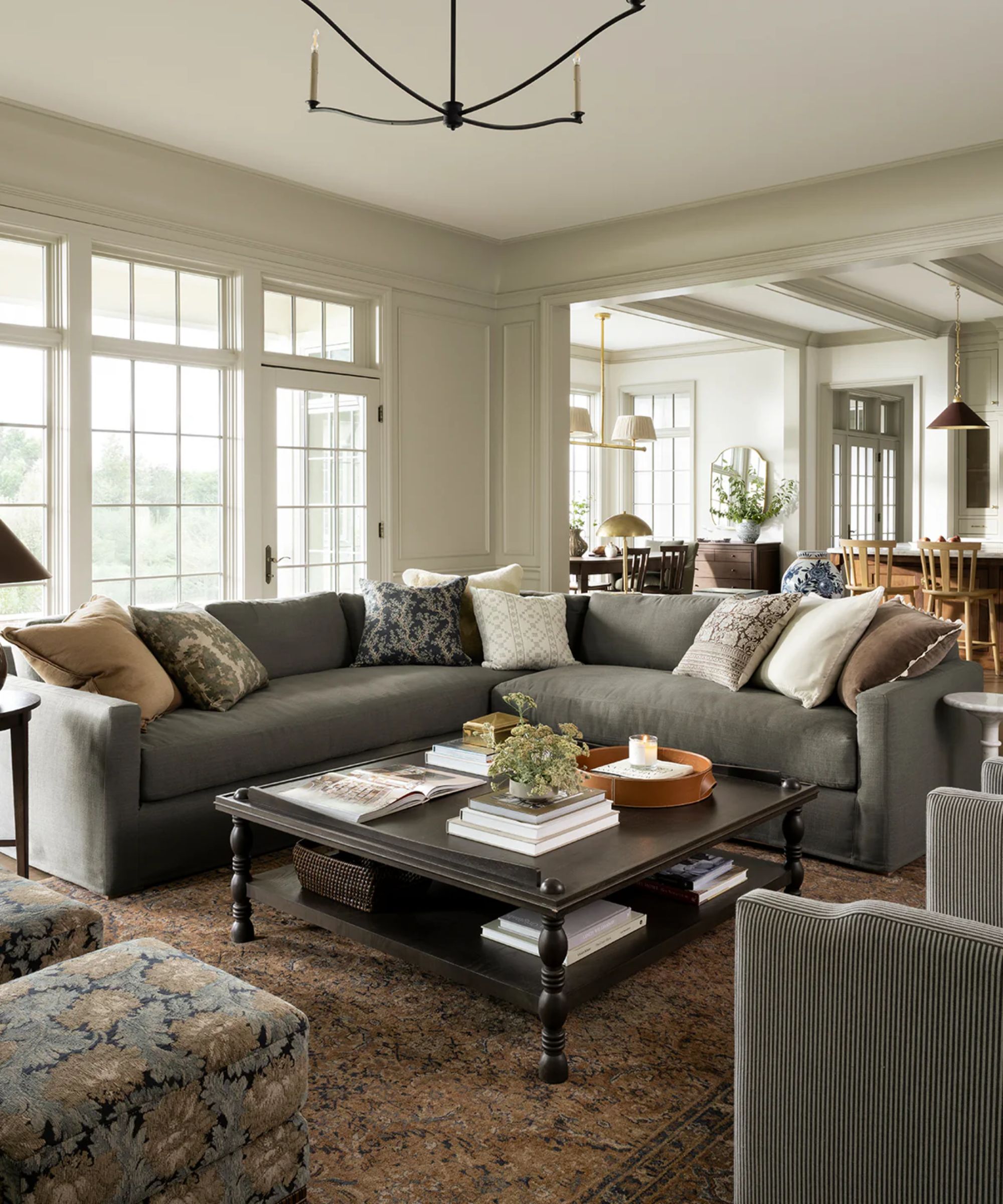 McGee &amp;amp; Co cozy neutral layered living room with a corner sofa, patterned throw pillows, a patterned vintage style rug and tapestry print ottomans