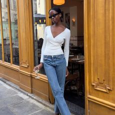 French influencer @sylviemus_ stands outside of a restaurant in Paris wearing black closed-toe heeled mules.