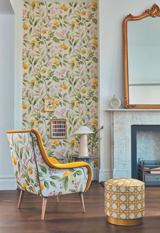living room with floral wallpaper with lemons, matching armchair, fireplace, mirror