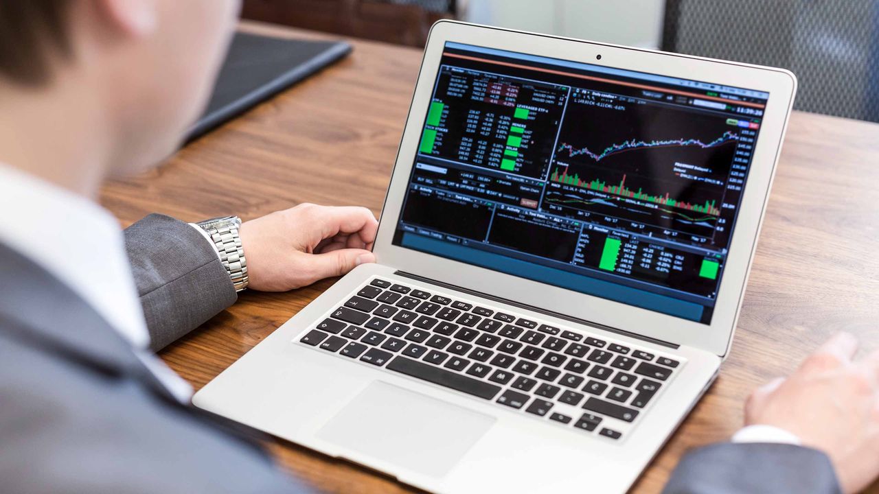 A businessperson looking at a stock chart on his laptop.