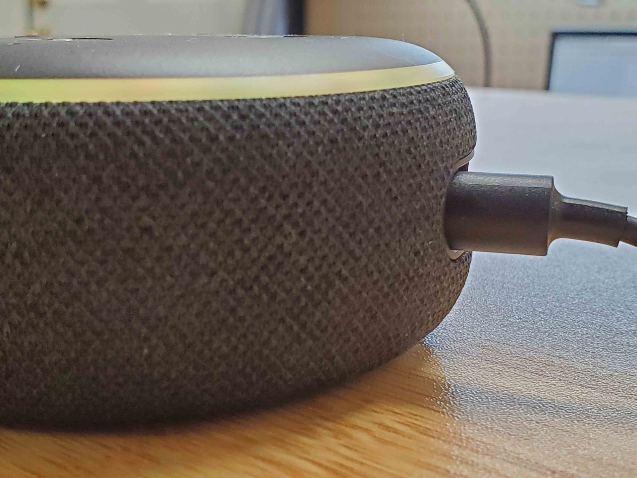 Close-up of Amazon Echo Dot third generation smart speaker with Alexa on light wooden surface, Lafayette, California, with charging cable visible