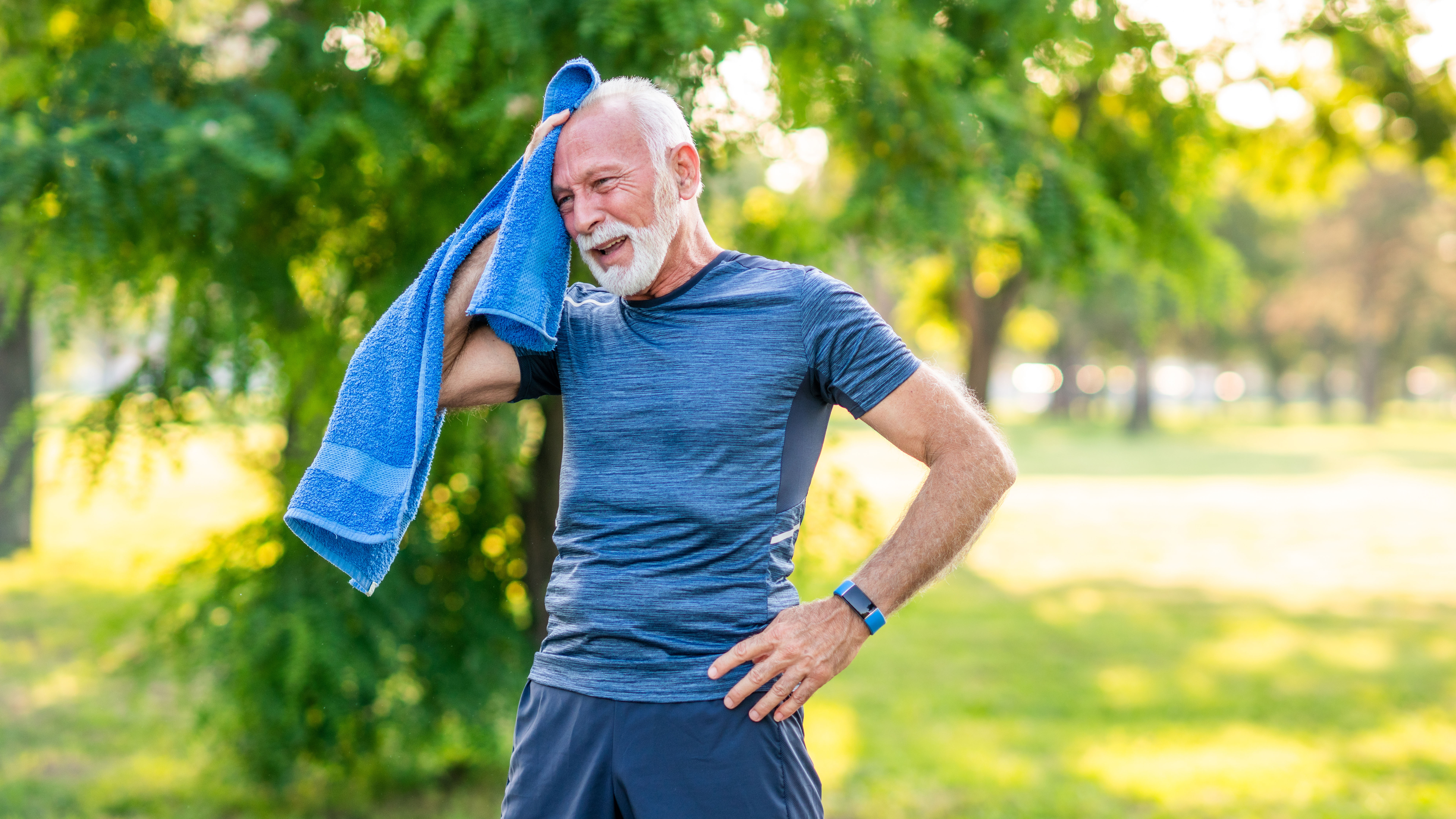 Older man wiping brow after exercising in park