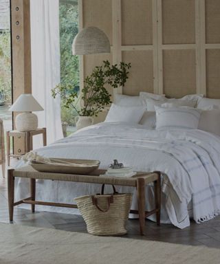 The White Company bedding on a bed against wooden walls.