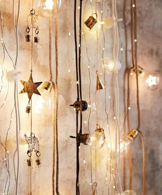 Scandinavian style bedroom fairy lights with star-shaped filaments, jute wires and plastic bulbs arranged on grey concrete wall