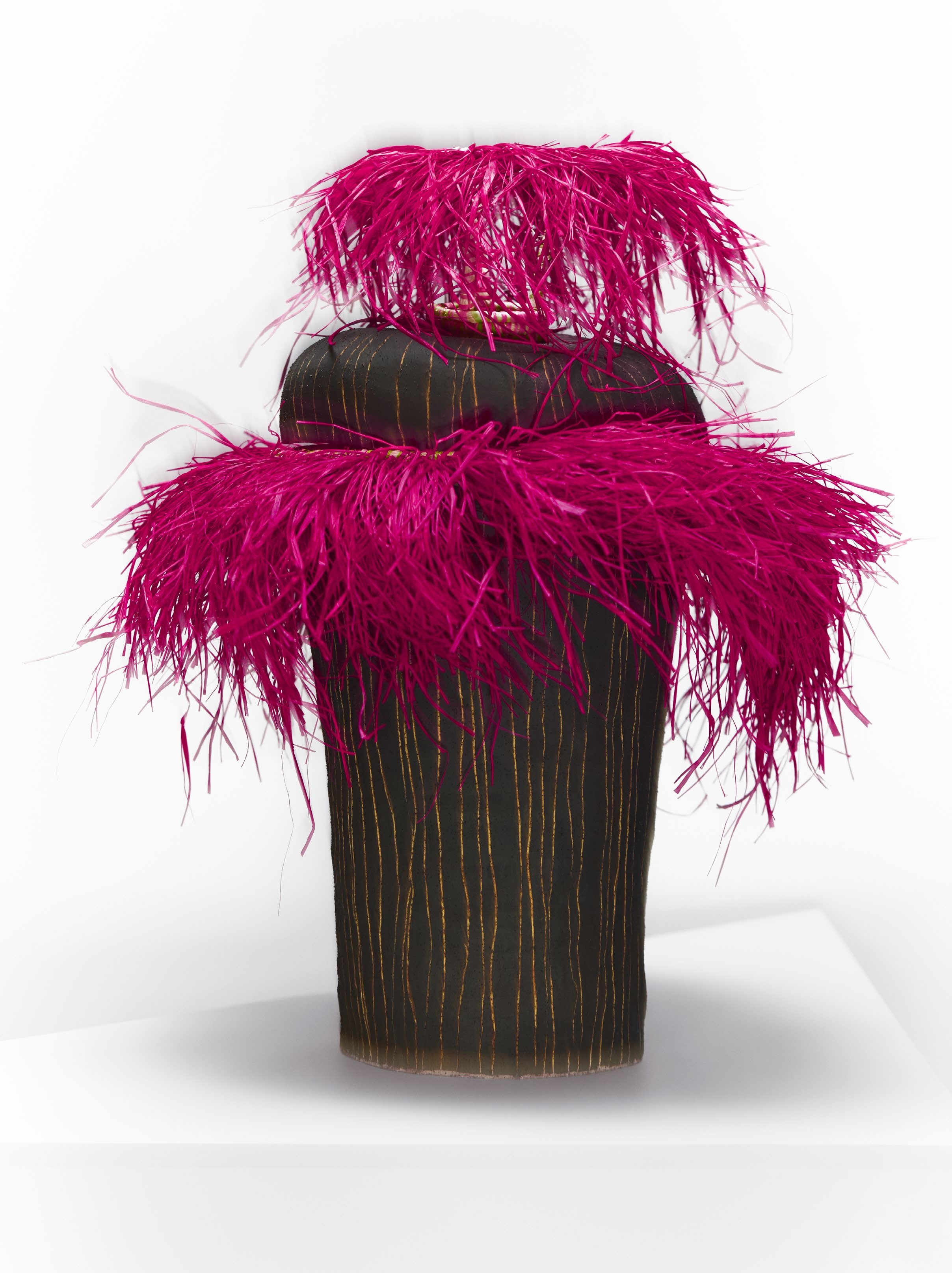 A sculptural piece by Adelaide artist Alfred Lowe, featuring a dark form adorned with vibrant magenta feathers, reflecting themes of identity and landscape.
