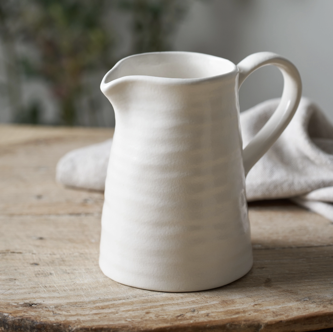 White ribbed ceramic jug on a wooden table