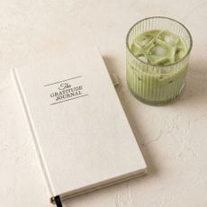 gratitude journal and an iced matcha in a glass