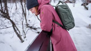 A woman looking over a bridge wearing a Fjallraven backpack