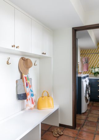 corner white mudroom with terracotta floor and pantry