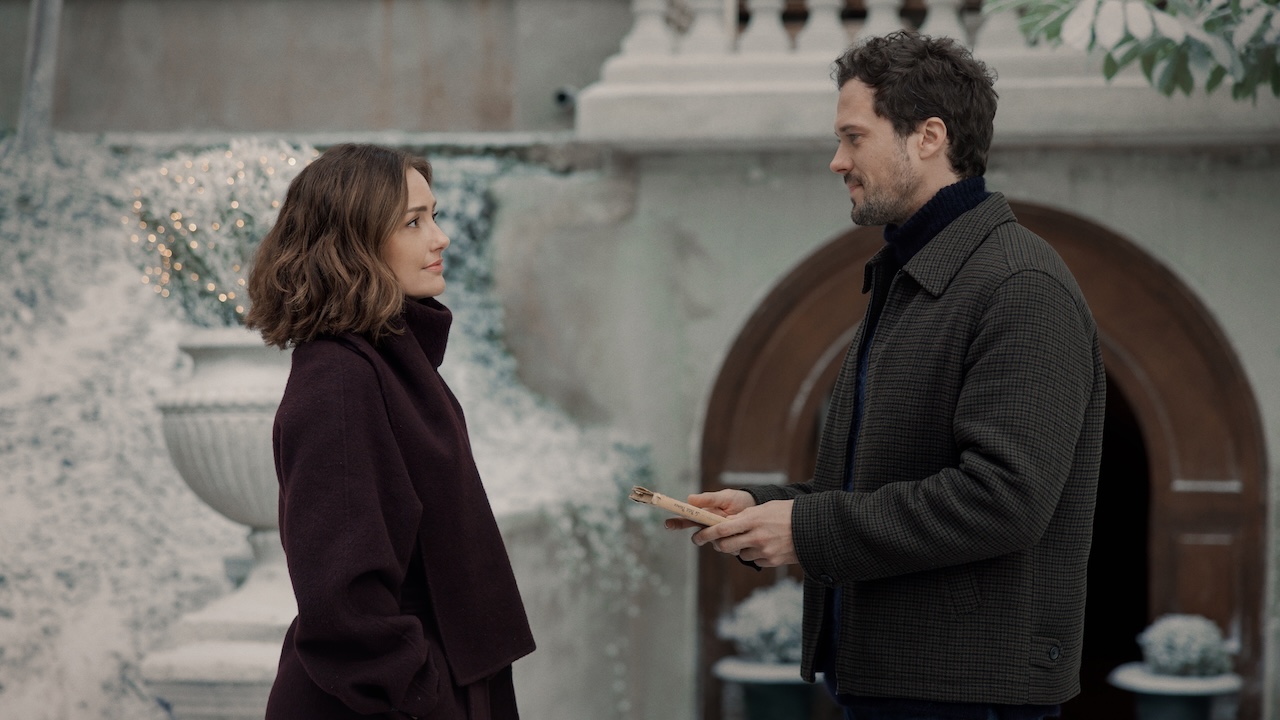 Henri accepting his childhood book from Sydney while they stand outside in the snow in Champagne Problems