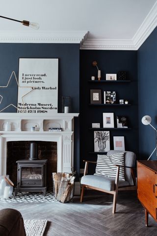 A navy blue living room with white fireplace and shelving in alcove, with prints dotted around