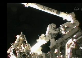 Astronaut Akihiko Hoshide by the space station robotic arm