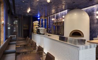 Babaji turkish restaurant with large stone pizza oven, rough blue ceramic tiles on walls and ceiling and brown tables and chairs